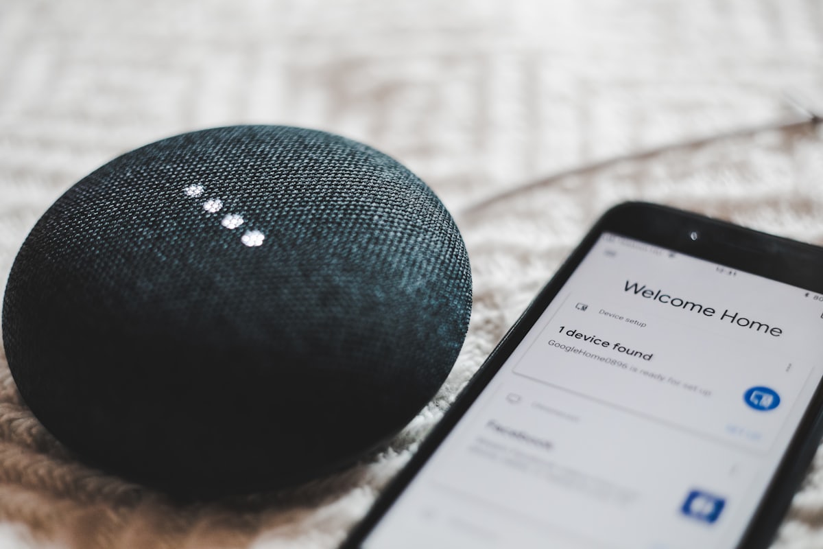 Sprachassistenten und Datenschutz: Smart Speaker mit leuchtender Statusanzeige neben einem Smartphone bei der Einrichtung